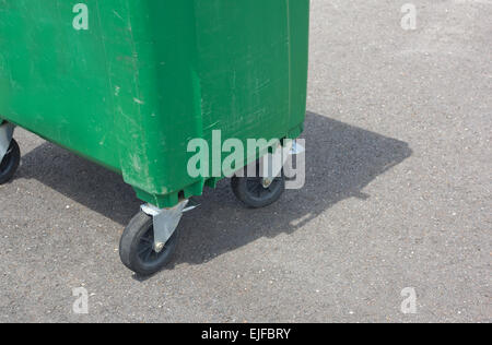 A green weathered dumpster at the street side. Wheels detail Stock Photo