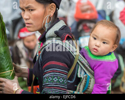 Young Hmong woman with a child at a market in Sapa, Vietnam Stock Photo