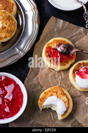 Cottage cheese pancakes with currant jam and sour cream, selective focus, top view Stock Photo