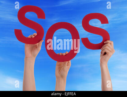 Many Caucasian People And Hands Holding Red Letters Or Characters Building The English Word Sos On Blue Sky Stock Photo
