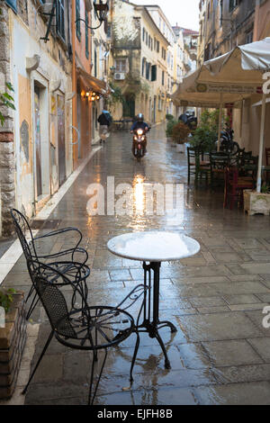 Deserted cafe table and chairs in rainy day scene in Kerkyra, Corfu Town, Greece Stock Photo