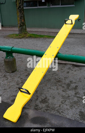 Children's yellow wooden seesaw or teeter-totter in a playground, Vancouver, Canada Stock Photo