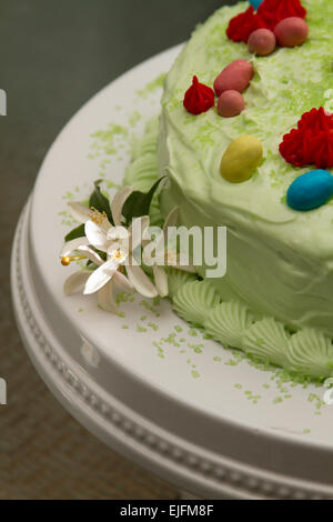 Easter cake colored in green to resemble grass, decorated with red flower and easter eggs, with a cream cheese frosting Stock Photo