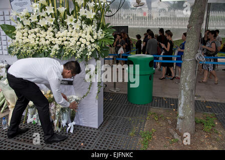 People pay respect and condolences with flowers and cards as a huge queue has formed in central Singapore as thousands wait to pay tribute to late statesman Lee Kuan Yew lying in state in parliament. Stock Photo