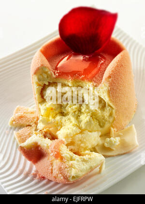 White chocolate cake with a sponge case and strawberry filling, covered with pink white chocolate powder and coffee in a table setting Stock Photo