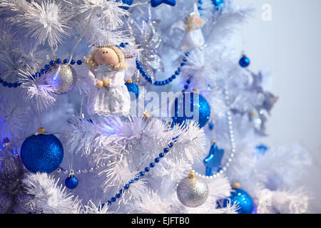 Christmas toys in the form of an angel hanging on the tree next to the balls and beads Stock Photo