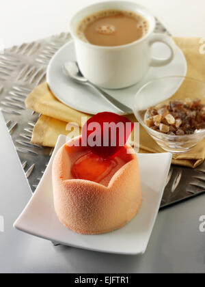White chocolate cake with a sponge case and strawberry filling, covered with pink white chocolate powder and coffee in a table setting Stock Photo