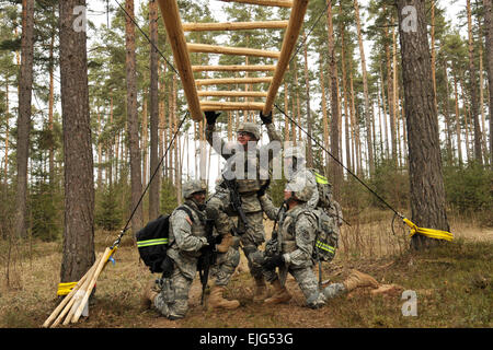 U.S. Army soldiers with 615th Military Police Company, 709th MP Battalion, get over an obstacle on the rugged terrain trail in Grafenwoehr, Germany, March 26, 2013. The RTT combines foot marching with obstacles and rapid elevation changes and is designed to replicate terrain in the current operating environment.  Visual Information Specialist Markus Rauchenberger/released Stock Photo