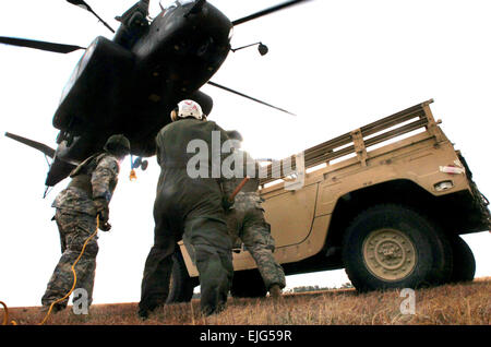 Petty Officer 1st Class Adrian Cristea center a crew chief from Helicopter Mine Countermeasures Squadron 14, assists Spcs. Justin McNeff left and Adam Haggett, from Company C, 3rd Battalion, 172nd Infantry Regiment, with hooking up a Humvee to a MH-53E Sea Dragon helicopter as part of a joint/combined Exercise Granite Triangle at Fort Pickett, Va., Feb. 21.  Staff Sgt. Jon Soucy Stock Photo