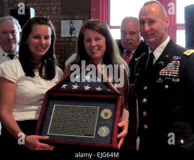 Col. Ralph Kauzlarich, former 1st Infantry Division Strategic Effects Chief, presents a flag to Jessica Bucca-Huges and Eve Bucca following a ceremony conducted Sept. 11 at Ground Zero in New York honoring those who died in the World Trade Center Sept. 11, 2001. The flag, one of the last ones flown above Camp Bucca, Iraq, before the camp was closed on Dec. 29, 2010, was presented to Jessica and Eve to celebrate the life of their father/husband Ronald Paul Bucca for whom the Iraqi camp was named. Ron Bucca, an Army Special Forces veteran, military policeman and New York City Fire Marshal, was k Stock Photo