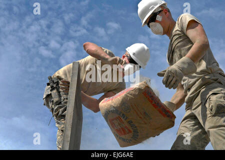 U.S. Army Spc. Michael McGovern, left, tosses a full bag of cement to U.S. Army Pfc. Dustin Mackiewicz, right, atop a cement mixer at a medical clinic construction site in Haiti, May 29, 2011. McGovern and Mackiewicz are assigned to the 716th Engineer Company. Fifty-eight Reserve Soldiers from the 716th teamed up with the Belizean engineers in Haiti to help build two medical clinics, a school, and one latrine facility as part of Task Force Bon Voizen. U.S. Army  Sgt. 1st Class Phillip Eugene Stock Photo