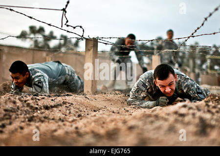 During a team-building challenge, U.S. Army 1st Lt. Alan Roy, right, and Sgt. Luis Garcia crawl through an obstacle course on Camp Taji, Iraq, March 23, 2010. Roy, a platoon leader, and Garcia, a squad leader, are assigned to the 1st Cavalry Division's, Company F, 3rd Battalion, 227th Aviation Regiment, 1st Air Cavalry Brigade.  Sgt. Travis Zielinski Stock Photo