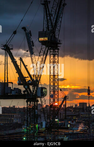 Silhouetted cranes over the Bloomberg Place construction site, London EC4, in the setting sun Stock Photo
