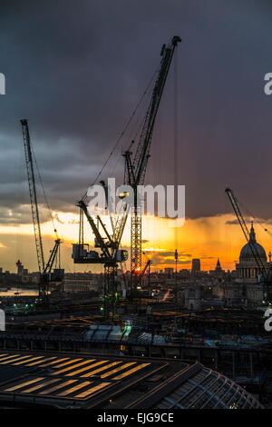 Silhouetted cranes over the Bloomberg Place construction site, London EC4, in the setting sun Stock Photo