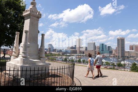 Couple walking past the Armistead Monument on Federal Hill overlooking Baltimore's Inner Harbor in Maryland. Stock Photo