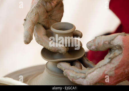 Close-up of potter's hands working  over potter's wheel with a little pot Stock Photo