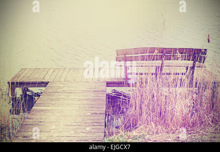 Vintage stylized photo of a wooden bench at the lake. Stock Photo