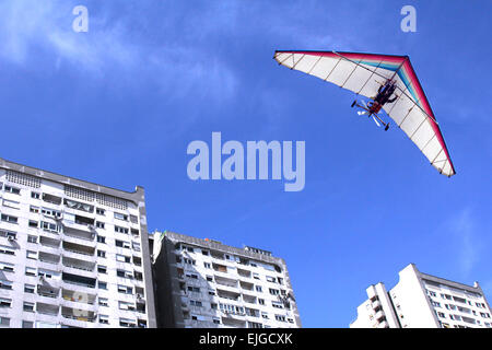 The motorized hang glider flying over residential buildings in the city Stock Photo