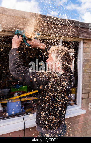 A Carpenter using an electric planer to plane some wood Stock Photo