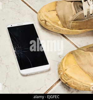 Broken smart phone over the tiles Stock Photo