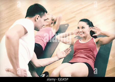 group of smiling women doing sit ups in the gym Stock Photo