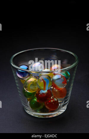 Colored marbles in glass on black background Stock Photo