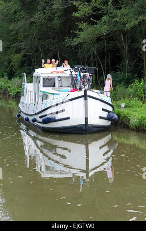 A family has moored their rented canal boat on the bank of the Canal du Centre upriver from Fragnes, France. Stock Photo