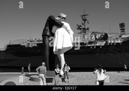 USS Midway on the waterfront in San Diego, and statue of Sailor Kissing Girl at the end of World War II Stock Photo