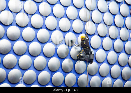 A workman cleaning the decorative discs on the exterior of the Selfridges building in Birmingham Stock Photo