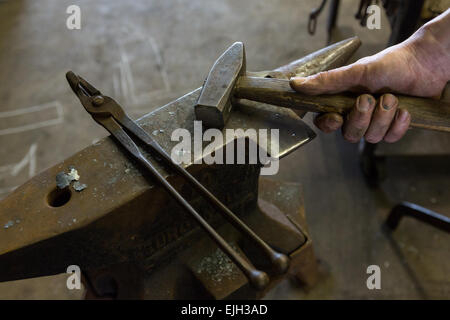 Blacksmiths hands on a hammer and anvil in a metal working shop in Charleston, SC Stock Photo