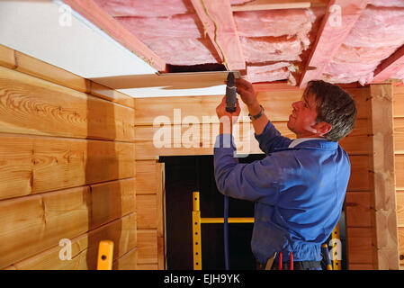 A Builder Staples Up Ceiling Tiles In The Ceiling Of A Lockwood