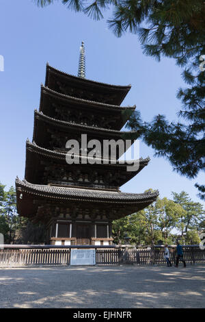 Couple in front of Japanese pagoda tower at Kofukuji temple in Nara, Japan. Pagoda framed by trees against a blue sky. Stock Photo