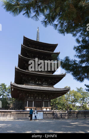 Couple in front of Japanese pagoda tower at Kofukuji temple in Nara, Japan. Pagoda framed by trees against a blue sky. Stock Photo