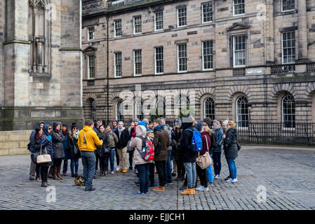 A group of tourists on a guided walking tour visit Parliament Square on the Royal Mile in Edinburgh, Scotland, UK. Stock Photo