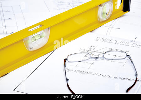 A set of blueprints with  reading glasses and a yellow level Stock Photo