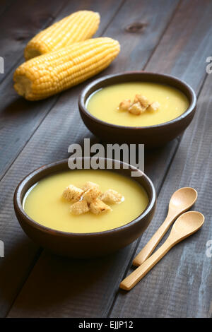 Two bowls of cream of corn soup with croutons on top, photographed on dark wood with natural light (Selective Focus) Stock Photo