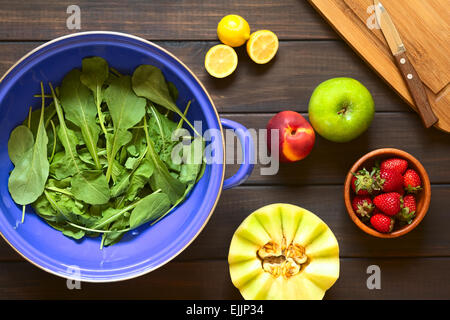 Overhead shot of rucola (lat. Eruca sativa) leaves in blue metal strainer with fresh fruits Stock Photo