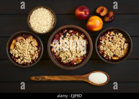Overhead shot of three rustic bowls filled with baked plum and nectarine crumble or crisp, photographed with natural light Stock Photo