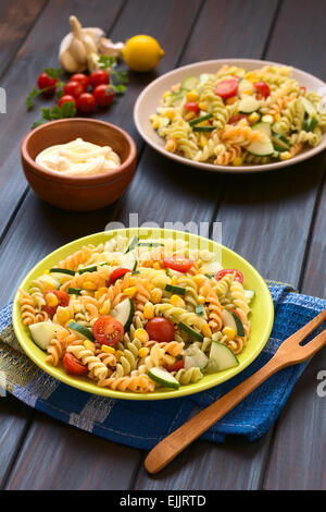 Two plates of vegetarian pasta salad made of tricolor fusilli, sweet corn, cucumber and cherry tomato with mayonnaise in back Stock Photo