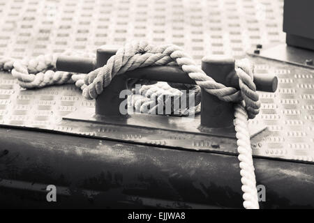 Black steel bollard with ropes mounted on a ship deck, monochrome photo Stock Photo