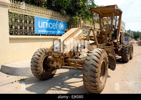 A Caterpillar motor grader is parked in front of the UNICEF office on a city street in Kampong Cham, Cambodia. Stock Photo