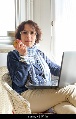 a senior woman eating an apple and looking the camera Stock Photo