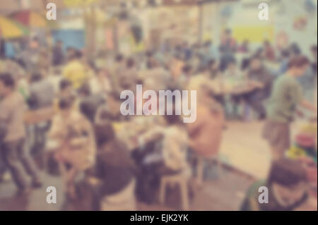 Blurred background of many people eating outside in the street. Designed to work with text overlays including white text Stock Photo