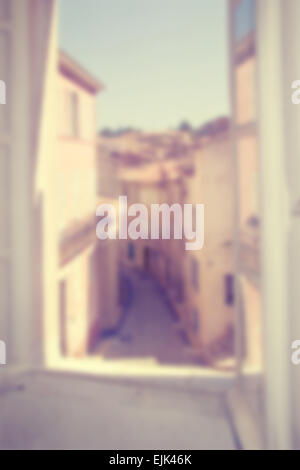 Blurred background of view from a window overlooking a narrow street in a small town. Works with text overlays including white. Stock Photo