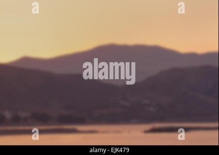 Blurred background of hills and mountains at sunset  with sea in the foreground. Designed to work with text overlays including t Stock Photo