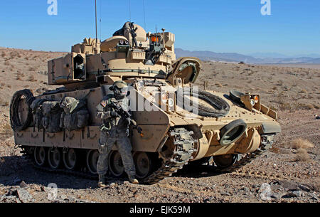 U.S. Army soldier from the 3rd Armored Brigade Combat Team, 1st Infantry Division pulls security next to a M2 Bradley Infantry Fighting Vehicle during Decisive Action rotation 13-03, Jan. 19, 2013, at the National Training Center in Fort Irwin, Calif. Decisive Action rotations are geared toward an adaptive enemy in a complex environment.  Sgt. Eric M. Garland II Stock Photo