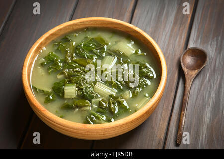 Chard soup in wooden bowl with a small wooden spoon, photographed on dark wood with natural light (Selective Focus) Stock Photo
