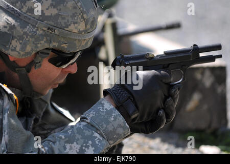 First Lt. Lyndon Hill, assigned to 30th Medical Command, fires the M9 pistol during U.S. Army Europe's Best Junior Officer Competition in Grafenwoehr, Germany, July 24, 2012. The BJOC, unique to the U.S. Army in Europe, is a training event for company-grade officers ranking from second lieutenant to captain meant to challenge and refine competitors' leadership and cognitive decision-making skills in a high-intensity environment. Stock Photo