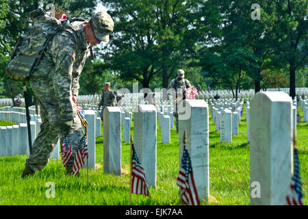 An Army soldier places a small American flag in front of a grave at Arlington National Cemetery, Va., May 26, 2011. The soldier is assigned to the 3rd U.S. Infantry Regiment, The Old Guard. Soldiers from the unit placed flags in a tradition known as &quot;flags in&quot; in front of more than 260,000 gravestones and about 7,300 niches at the cemetery's columbarium in about three hours. The Old Guard has maintained this tradition since it was designated the Army's official ceremonial unit in 1948. U.S. Army courtesy photo Stock Photo