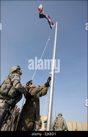 Spc. Anthony Perez of Troop B, 5th Squadron, 4th Cavalry Regiment, 2nd Heavy Brigade Combat Team, 1st Infantry Division, Multi-National Division-Baghdad, and an Iraqi Soldier from the 2nd Battalion, 22nd Brigade, 6th Iraqi Army Division raise the Iraqi flag above Joint Security Station Ghazaliyah III in the Ghazaliyah district of northwest Baghdad Jan. 1. Stock Photo
